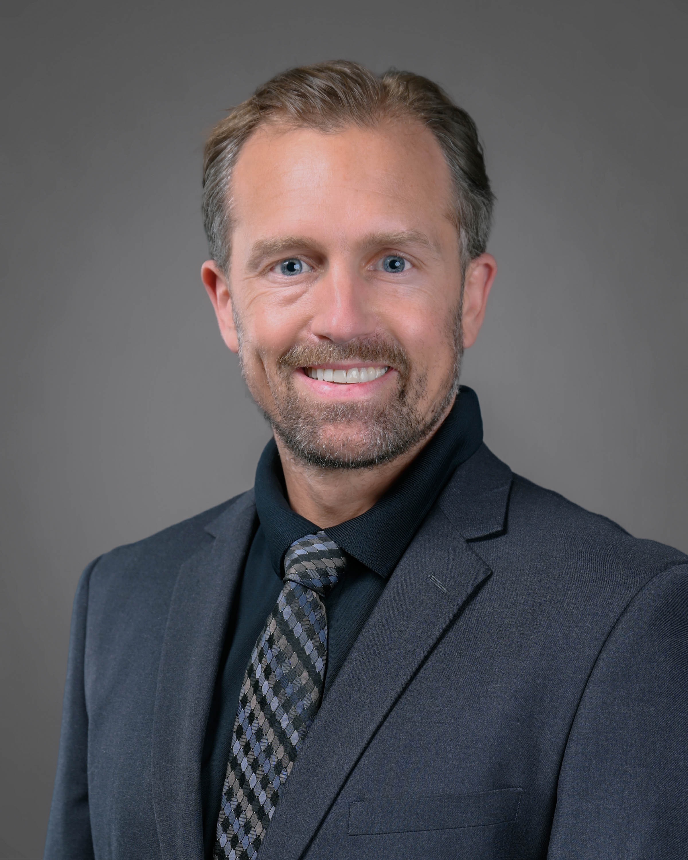 Light brown-haired man with a beard smiling.